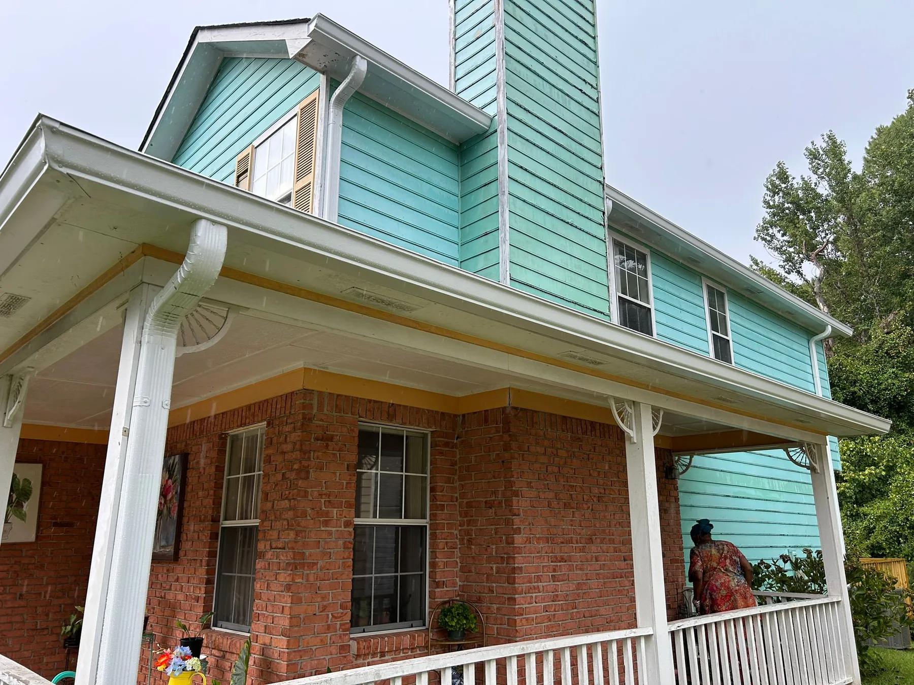 Completed gutter installation on a home with a covered wraparound porch