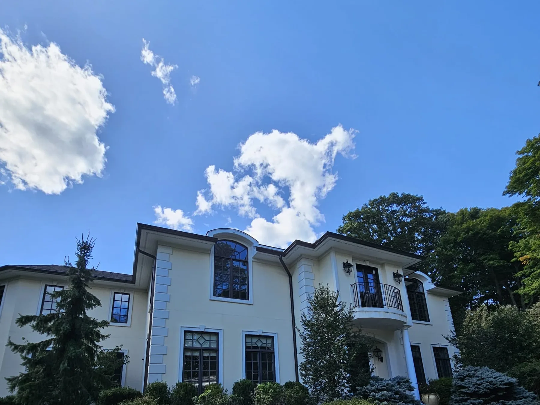 Completed gutter installation on a large home with a covered balcony