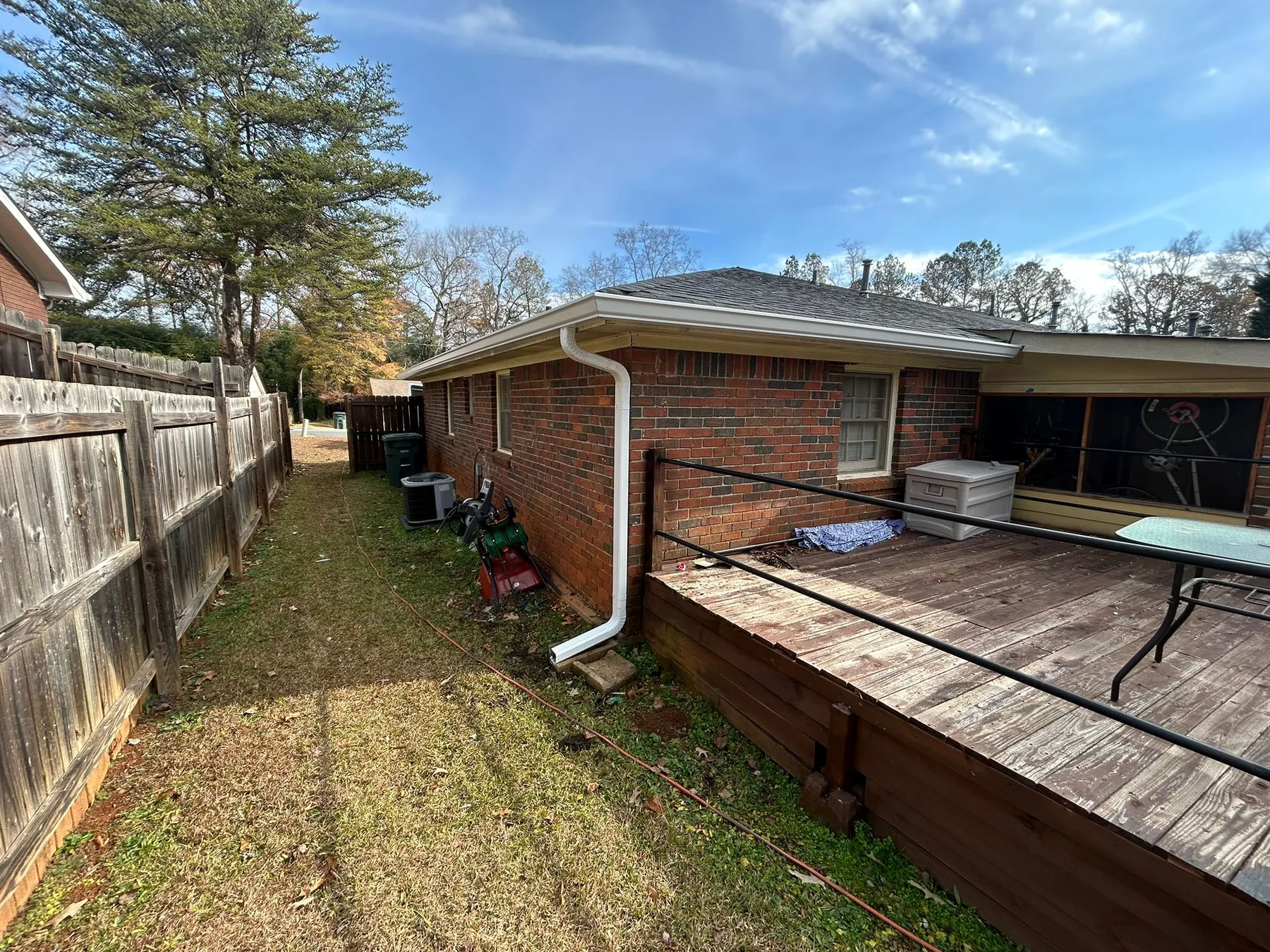 Gutter installation along a brick home's side yard and deck