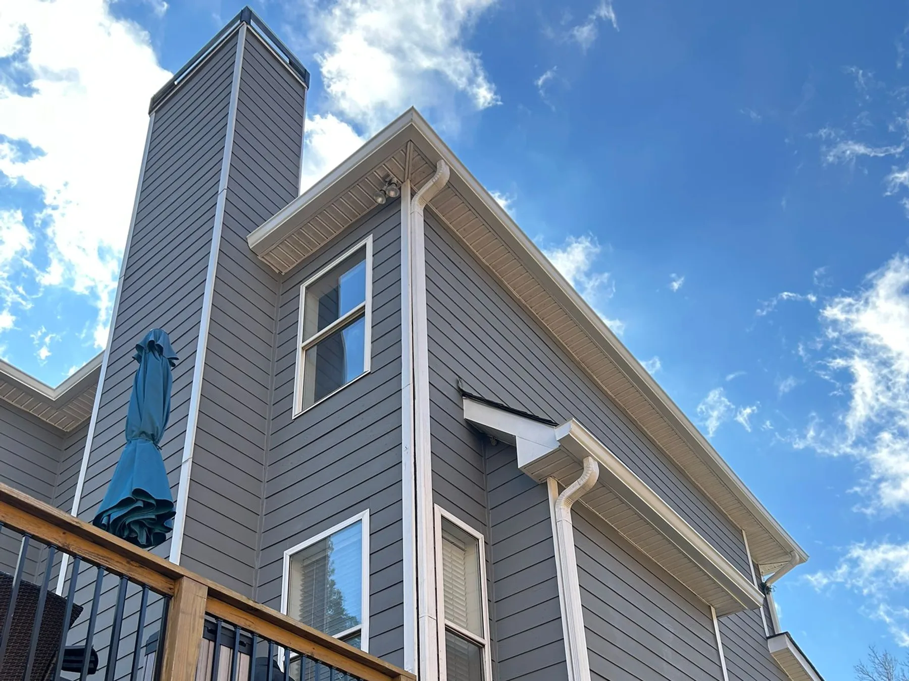 Completed gutters on a gray home with a tall chimney